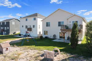 Back of property featuring a patio, a balcony, a lawn, a playground, and central air condition unit