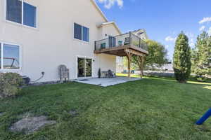 Back of property with a lawn, a patio, a deck, and central AC