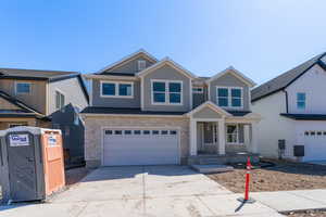 Craftsman inspired home featuring concrete driveway, stone siding, and an attached garage