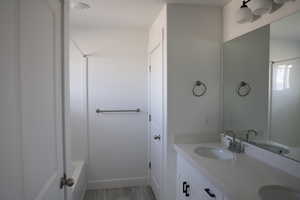 Bathroom with a sink, double vanity, and wood finished floors