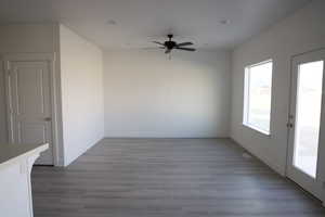 Empty room featuring baseboards, dark wood-style floors, and a ceiling fan