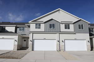 View of property with stone siding, board and batten siding, concrete driveway, and entry steps