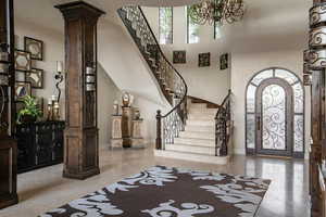 Entryway with stairway, a healthy amount of sunlight, a towering ceiling, and ornate columns