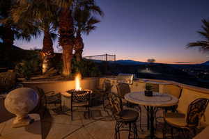 View of patio with a grill, an outdoor kitchen, a mountain view, and a fire pit