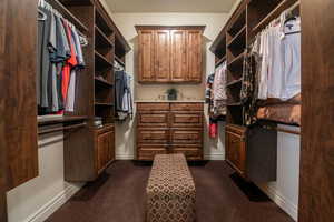 Walk in closet featuring dark colored carpet