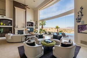 Living room featuring a large fireplace, a towering ceiling, visible vents, and plenty of natural light