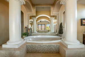 Full bath featuring tile patterned floors, vanity, a ceiling fan, a bath, and decorative columns