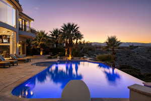 Pool at dusk with an infinity pool, a mountain view, and a patio area