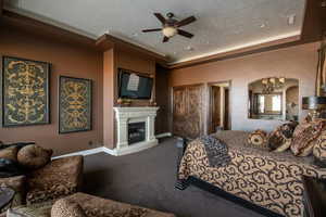 Carpeted bedroom featuring crown molding, a fireplace with raised hearth, an inviting chandelier, baseboards, and arched walkways