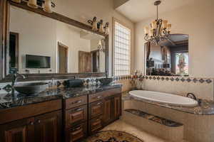 Bathroom with a sink, a garden tub, double vanity, tile patterned flooring, and a notable chandelier