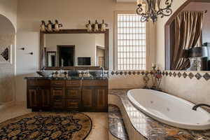 Bathroom featuring a whirlpool tub, a sink, double vanity, and tile patterned floors