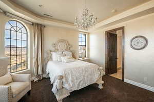 Bedroom featuring visible vents, baseboards, a tray ceiling, a notable chandelier, and carpet floors