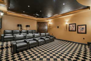 Home theater featuring baseboards, carpet, and a raised ceiling