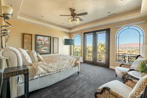 Bedroom with dark colored carpet, multiple windows, a tray ceiling, and access to outside