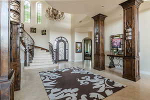 Entryway featuring arched walkways, marble finish floor, stairway, a high ceiling, and decorative columns