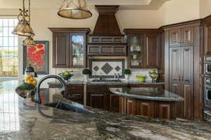 Kitchen featuring decorative light fixtures, glass insert cabinets, dark brown cabinets, and a sink