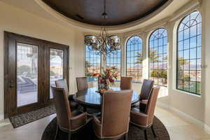 Dining space with baseboards, visible vents, an inviting chandelier, light tile patterned flooring, and a tray ceiling