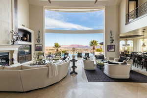 Living room featuring a large fireplace, a towering ceiling, and plenty of natural light