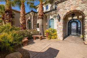 Property entrance with stucco siding, stone siding, and a patio