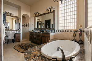 Bathroom featuring vanity, a whirlpool tub, and tile walls