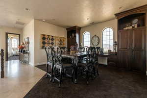 Dining area with baseboards, a textured ceiling, and visible vents