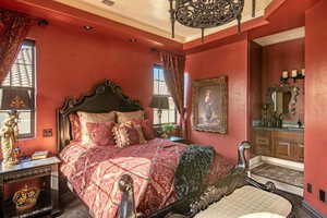 Bedroom featuring a raised ceiling, multiple windows, connected bathroom, and visible vents