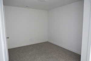 Spare room with baseboards, visible vents, and carpet floors