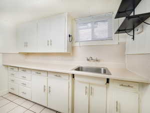 Kitchen featuring sink, light tile patterned floors, and white cabinets