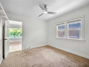 Carpeted empty room featuring ceiling fan