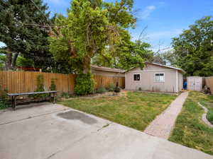 Back of property with a patio, a yard, and a storage unit