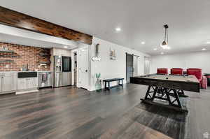 Rec room with a sink, a barn door, recessed lighting, and dark wood-type flooring