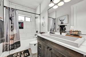 Full bathroom with vanity, toilet, and shower / bath combination with curtain