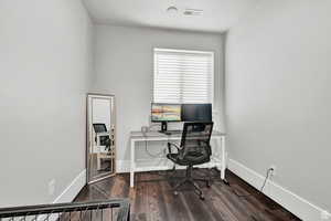 Office space with baseboards, dark wood-style floors, and visible vents