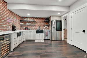 Kitchen featuring a sink, light countertops, appliances with stainless steel finishes, beverage cooler, and open shelves