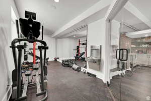 Exercise room featuring brick wall and baseboards