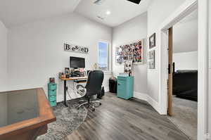 Office space with wood finished floors, visible vents, baseboards, ceiling fan, and lofted ceiling