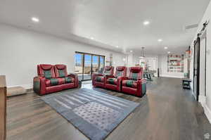 Living room with a textured ceiling, visible vents, dark wood-style flooring, and a barn door