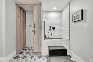 Full bath featuring baseboards, a textured ceiling, tiled shower, and tile patterned floors