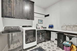 Washroom featuring a sink, light floors, cabinet space, and washer and dryer