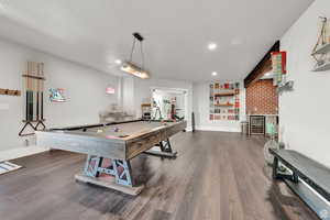 Rec room featuring recessed lighting, a bar, baseboards, dark wood-type flooring, and wine cooler