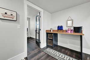 Office with dark wood finished floors, visible vents, and baseboards