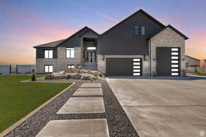 Modern home with board and batten siding, driveway, a yard, and a standing seam roof