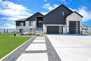 Contemporary house with an attached garage, a standing seam roof, driveway, board and batten siding, and a front yard