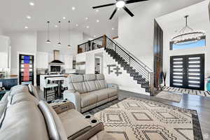 Living room with stairs, wood finished floors, french doors, recessed lighting, and high vaulted ceiling