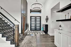 Entryway featuring a notable chandelier, baseboards, and dark wood-style flooring