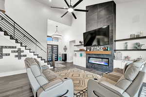 Living room with baseboards, stairs, dark wood-style floors, a high ceiling, and a fireplace