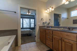 Bathroom with a washtub, ceiling fan, tile patterned flooring, and vanity