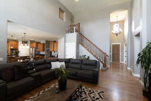 Living room featuring hardwood / wood-style flooring, a chandelier, and a towering ceiling