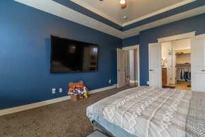 Bedroom with carpet, a tray ceiling, ornamental molding, ceiling fan, and a textured ceiling