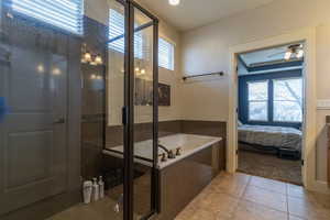 Bathroom with tile patterned floors, ceiling fan, vanity, and shower with separate bathtub